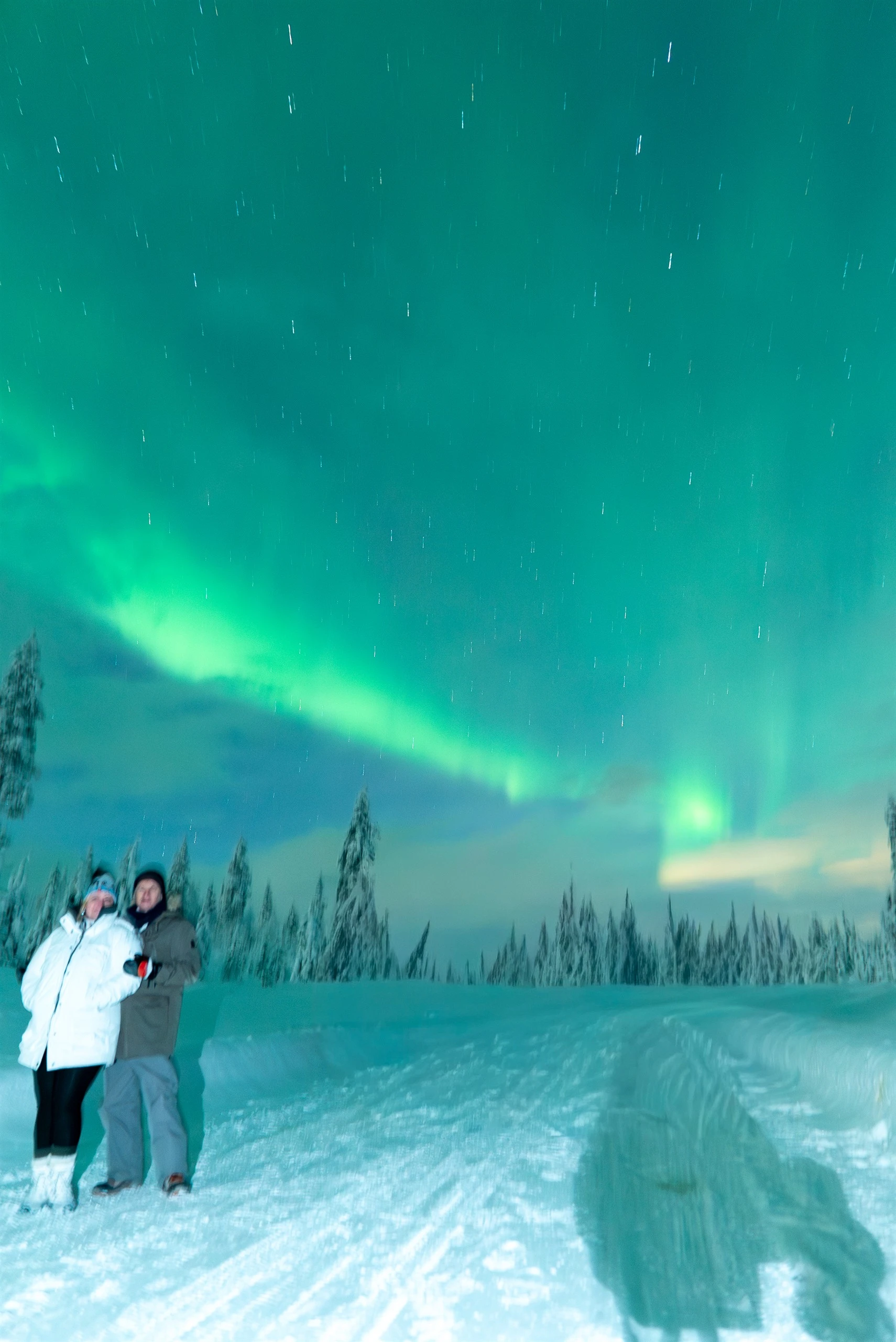 Aurora arc over a snowy track and guests in Finnish Lapland