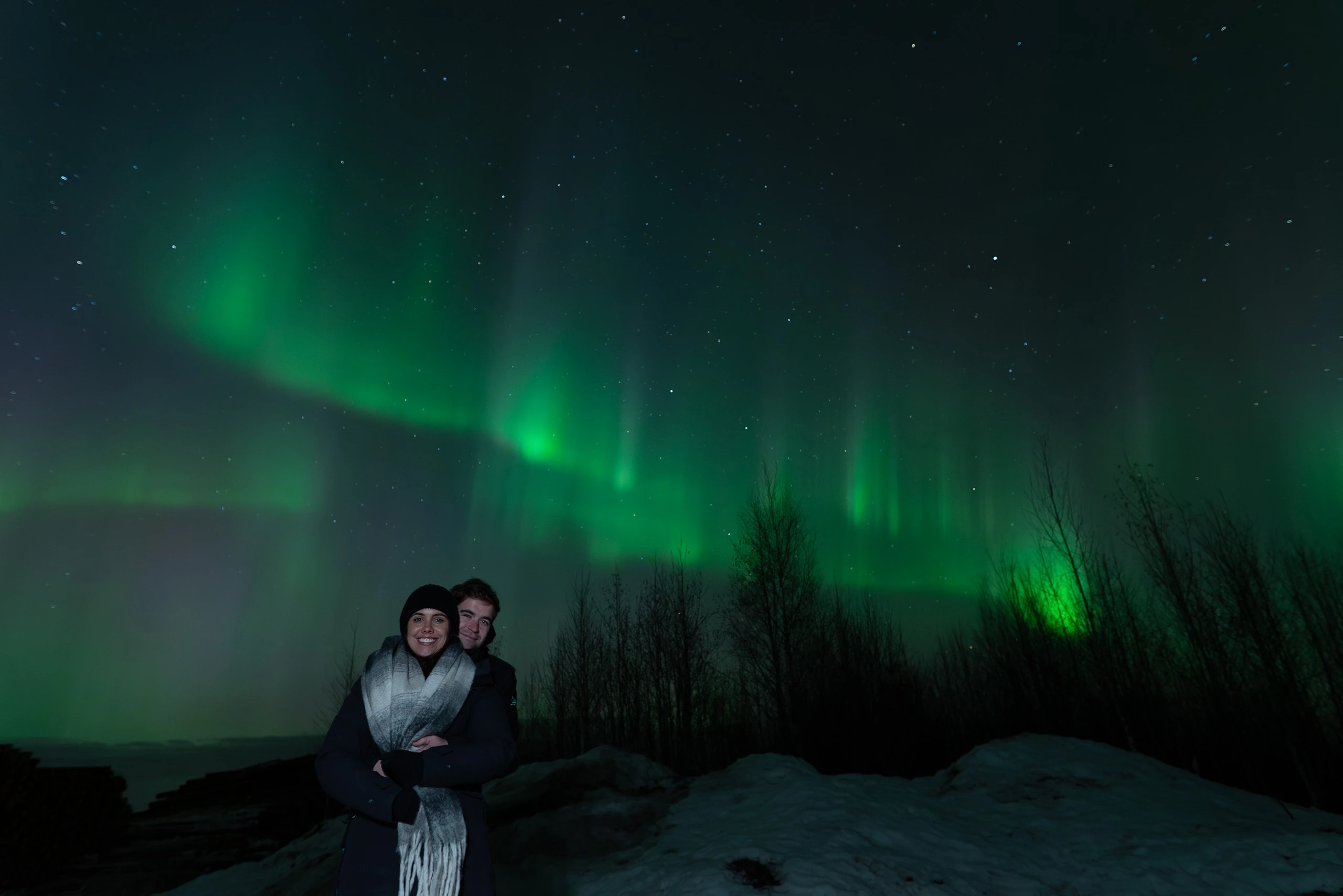 Couple watching a bright aurora arc in Lapland