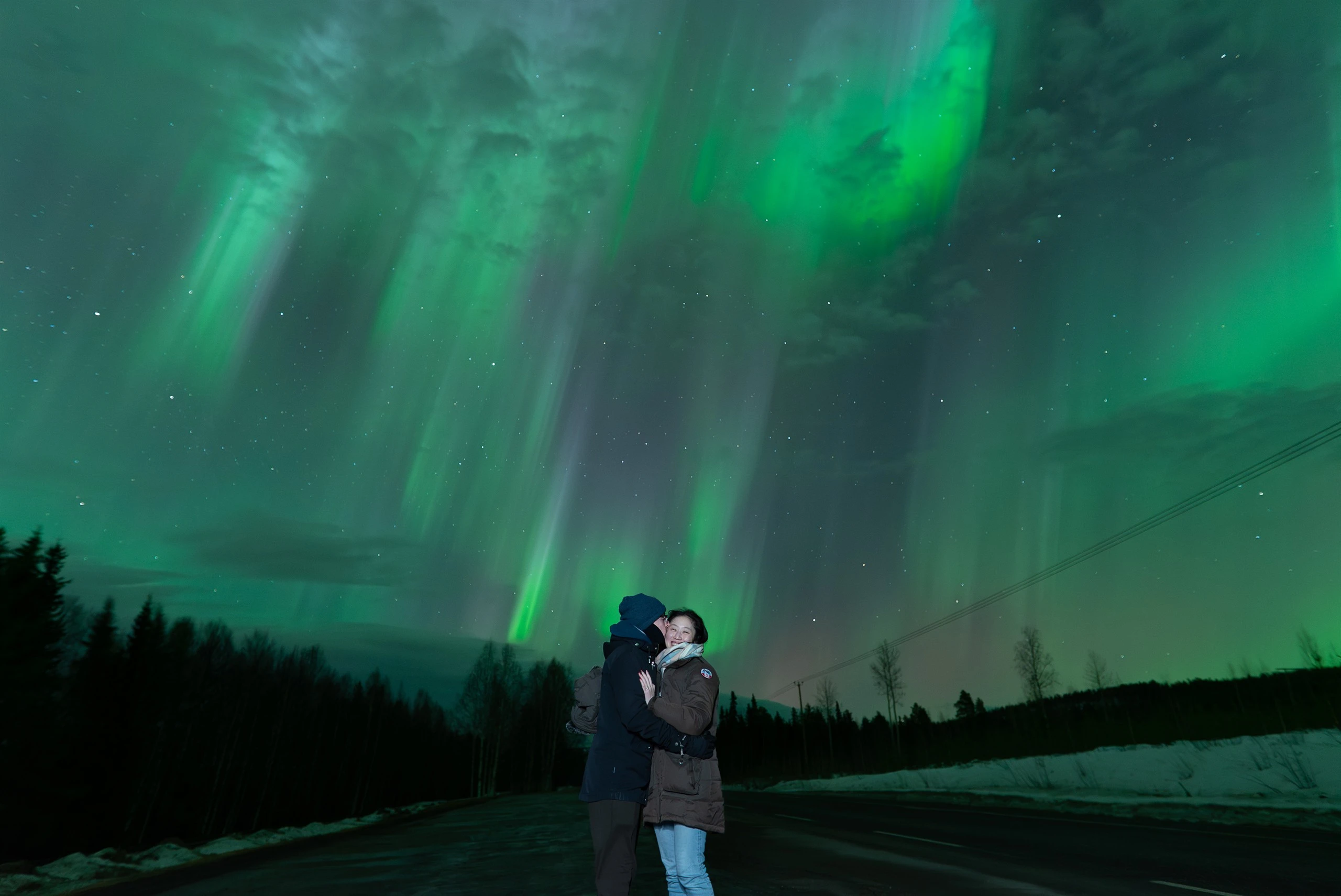 Couple under a swirling aurora corona in Lapland