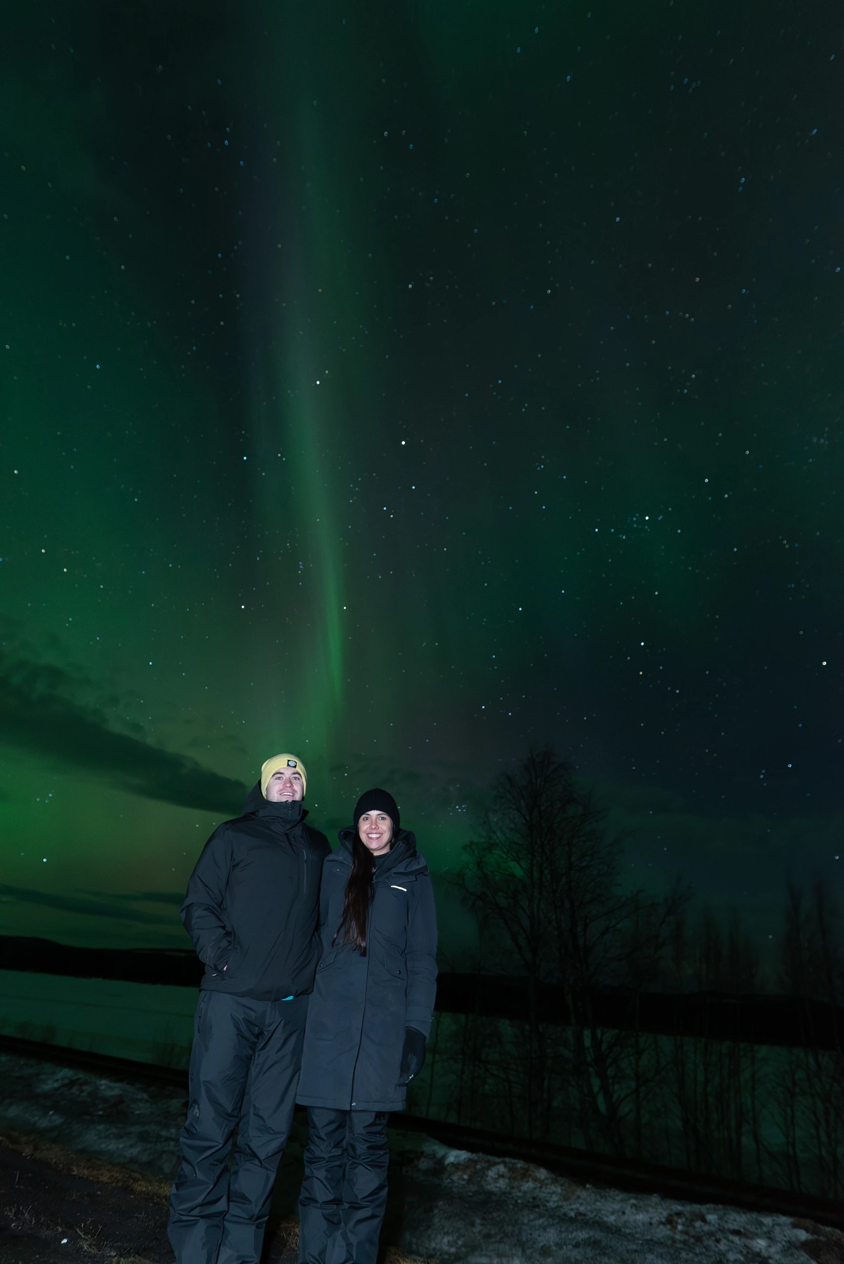 Couple under tall aurora pillars in Finnish Lapland