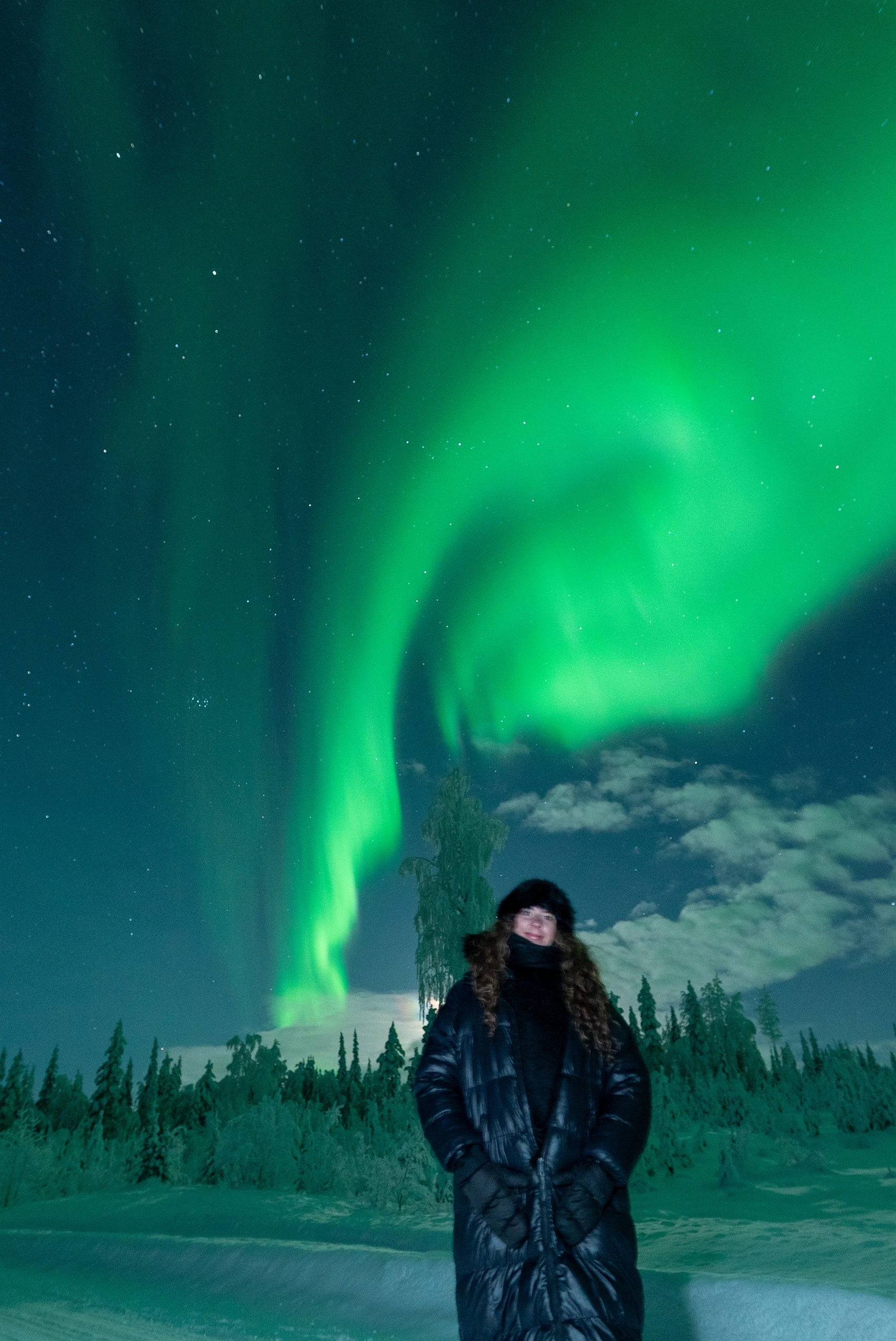 Guest under a huge aurora swirl on a northern lights hunt in Lapland