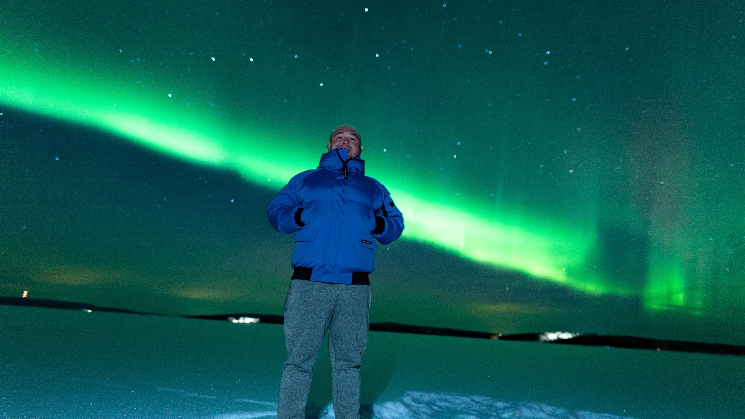 Green aurora arc over a frozen lake on a northern lights hunt in Ylläs