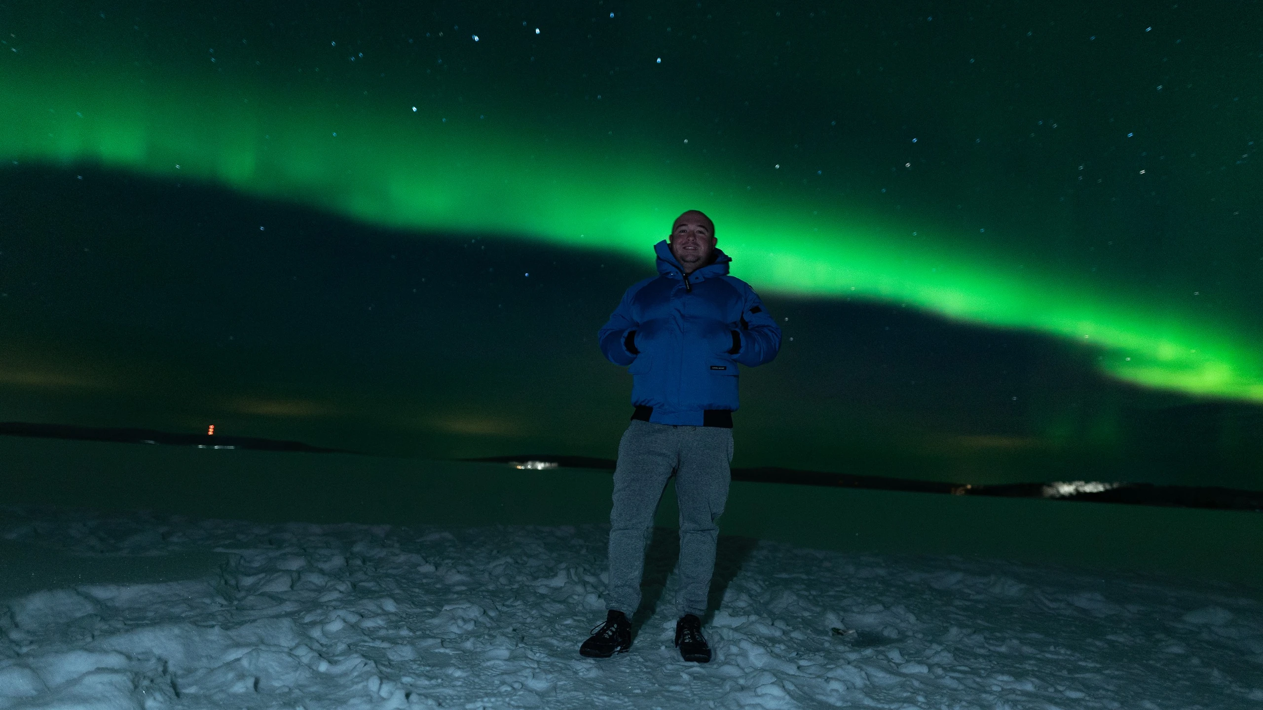 Guest standing on a frozen lake under the aurora borealis in Ylläs